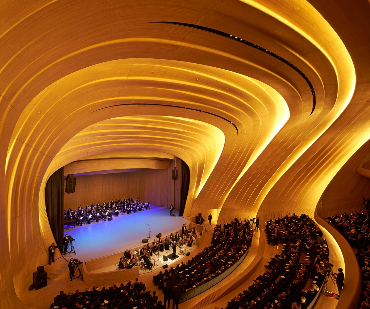 Audience and orchestra inside a curved timber concert hall